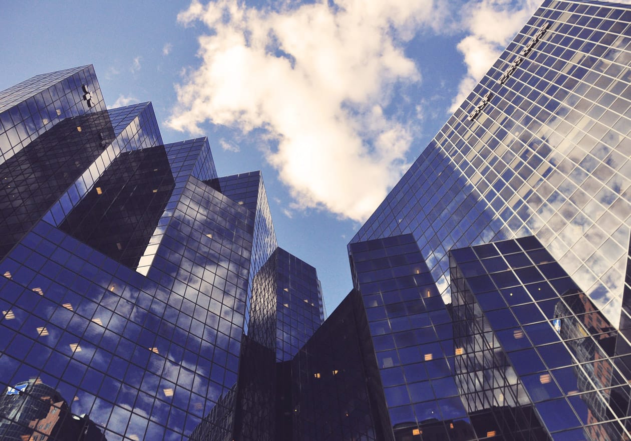 Looking up at skyscrapers with blue sky and clouds