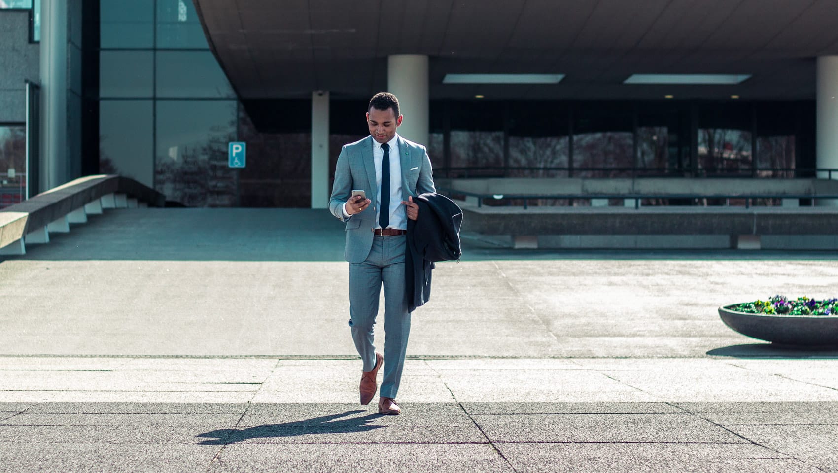 Man in a business suit walking while on his phone